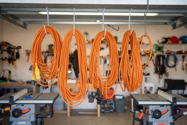 Heavy orange extension cords coiled on a garage hook