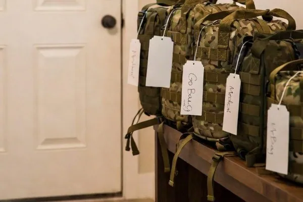 A packed evacuation bag with its contents laid out on a bed