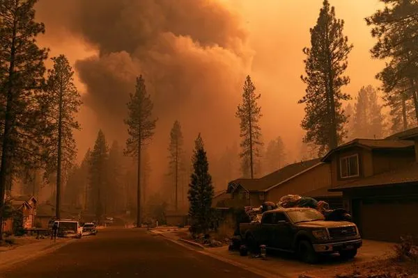Mountain West neighborhood street with wildfire smoke filling the sky and truck loaded with evacuation belongings