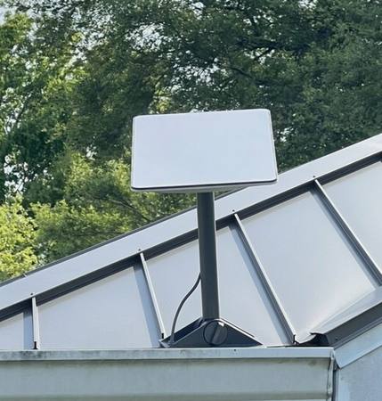 Real Starlink flat dish mounted on a metal roof ridge — actual residential installation showing how compact the dish is