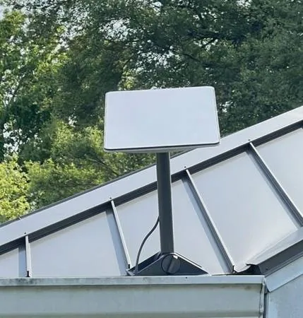 Real Starlink flat dish mounted on a metal roof ridge — actual residential installation showing how compact the dish is