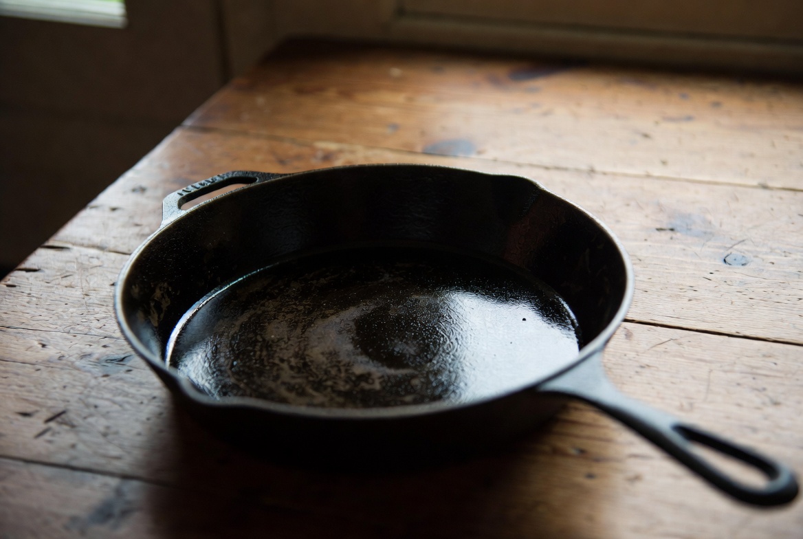 An old, well-worn cast iron skillet with a deep black patina from generations of use
