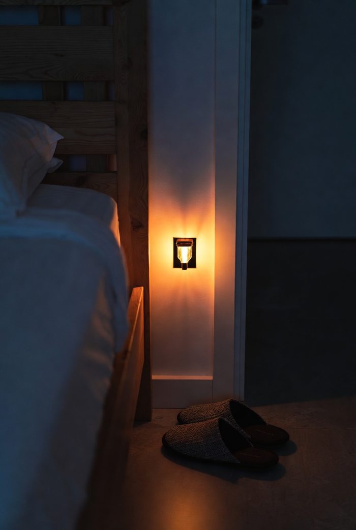 Slippers placed beside the bed at night in the warm glow of a plug-in motion night light by the doorway