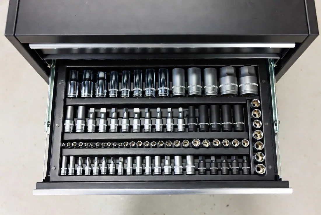 A tool cabinet drawer pulled open from above showing shallow and deep sockets standing in size order in their racks