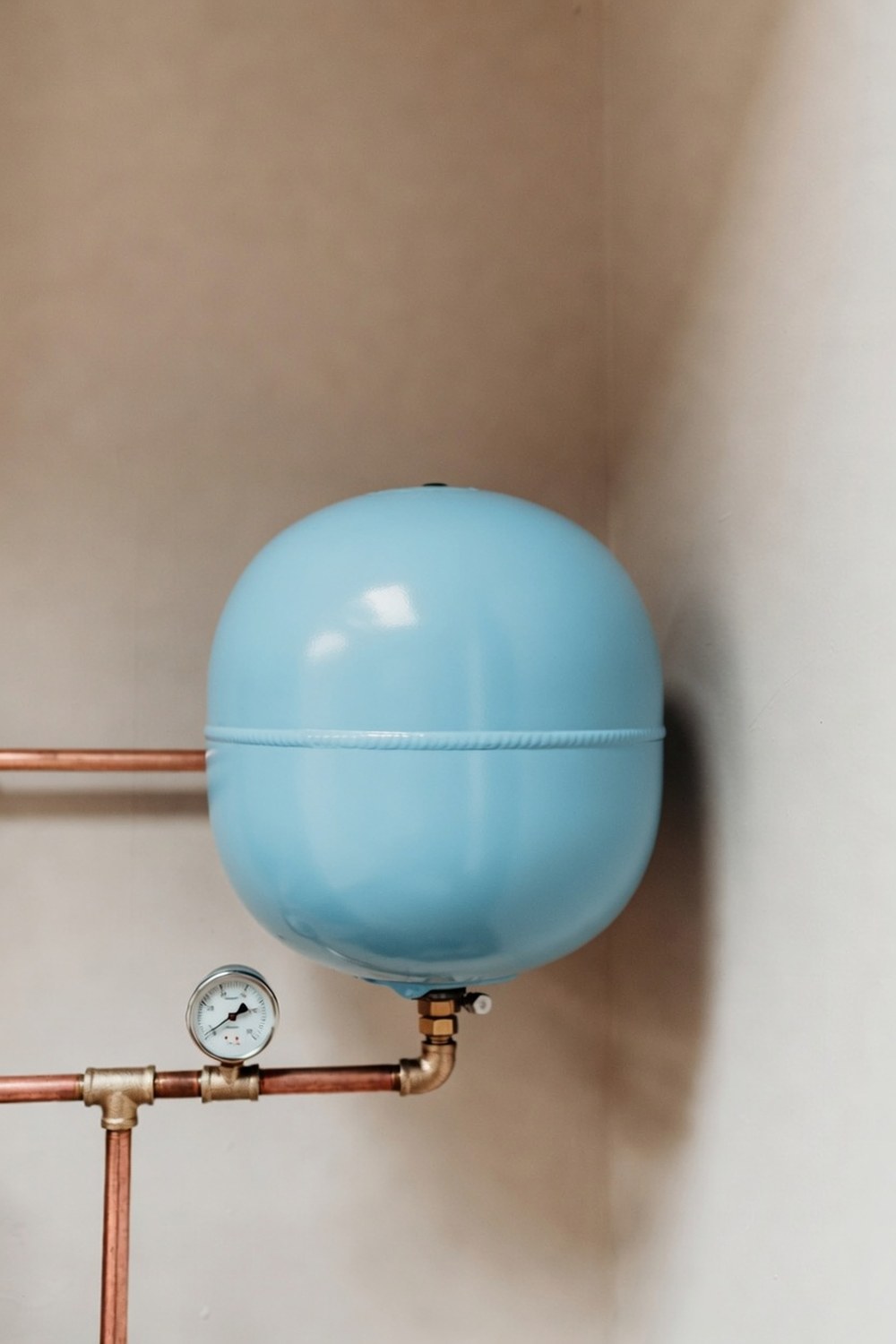 A small pressure tank about the size of a soccer ball mounted on household water piping